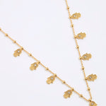 Gold necklace with hamsa hand charms on a white background