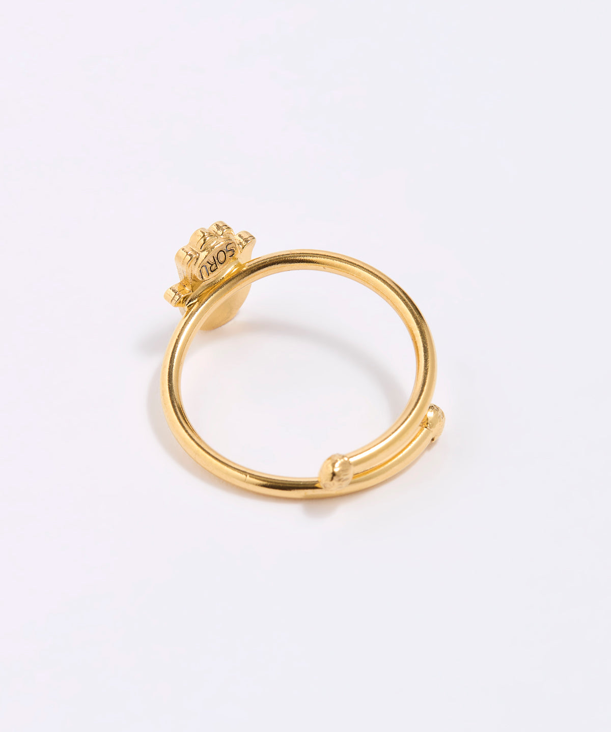 back shot of Gold coloured ring with a hamsa hand design on a white background