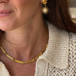 Close-up of a person wearing gold coloured necklace and earrings 