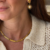 Close-up of a person wearing gold coloured necklace and earrings 