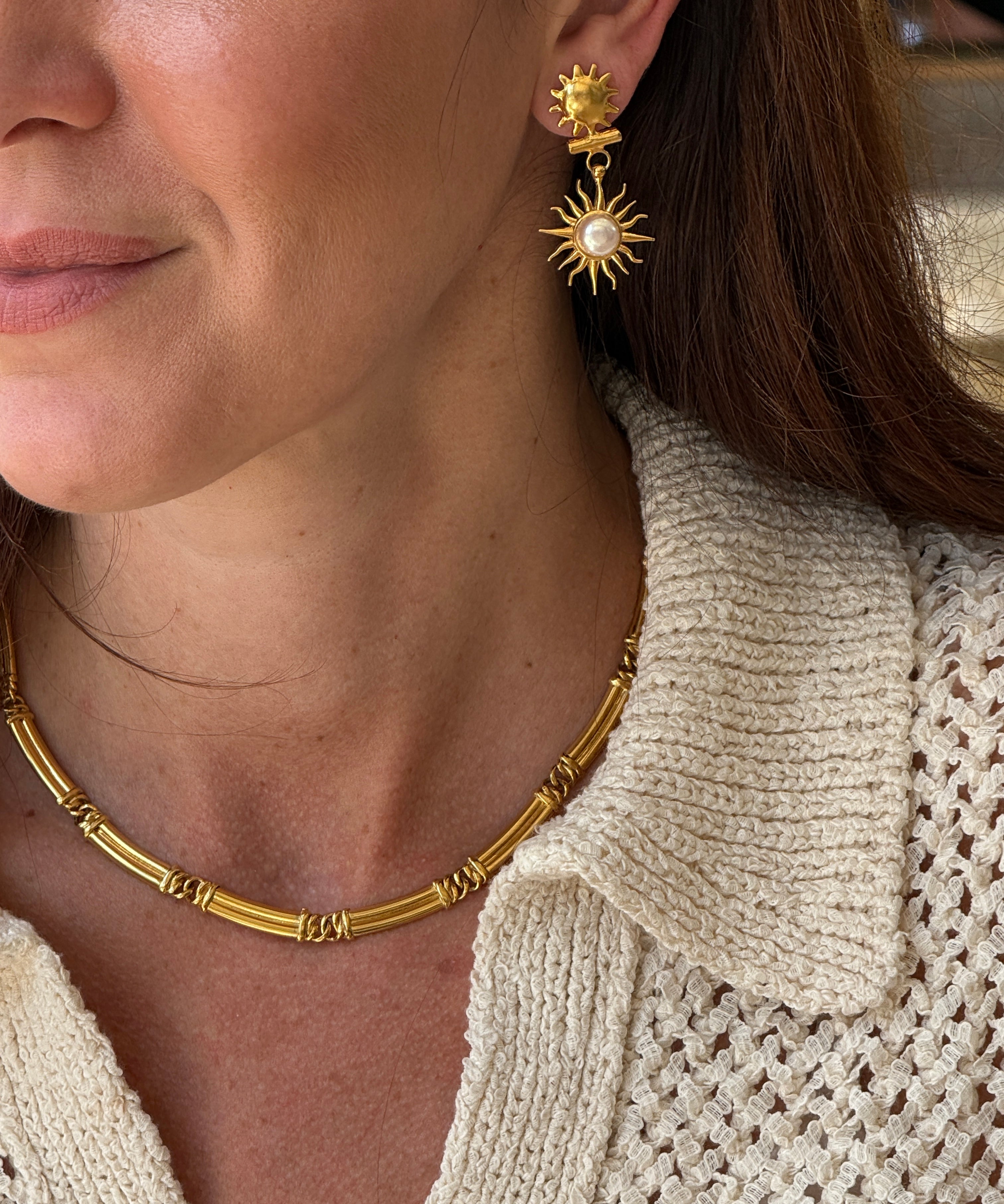 Close-up of a person wearing gold coloured necklace and earrings 