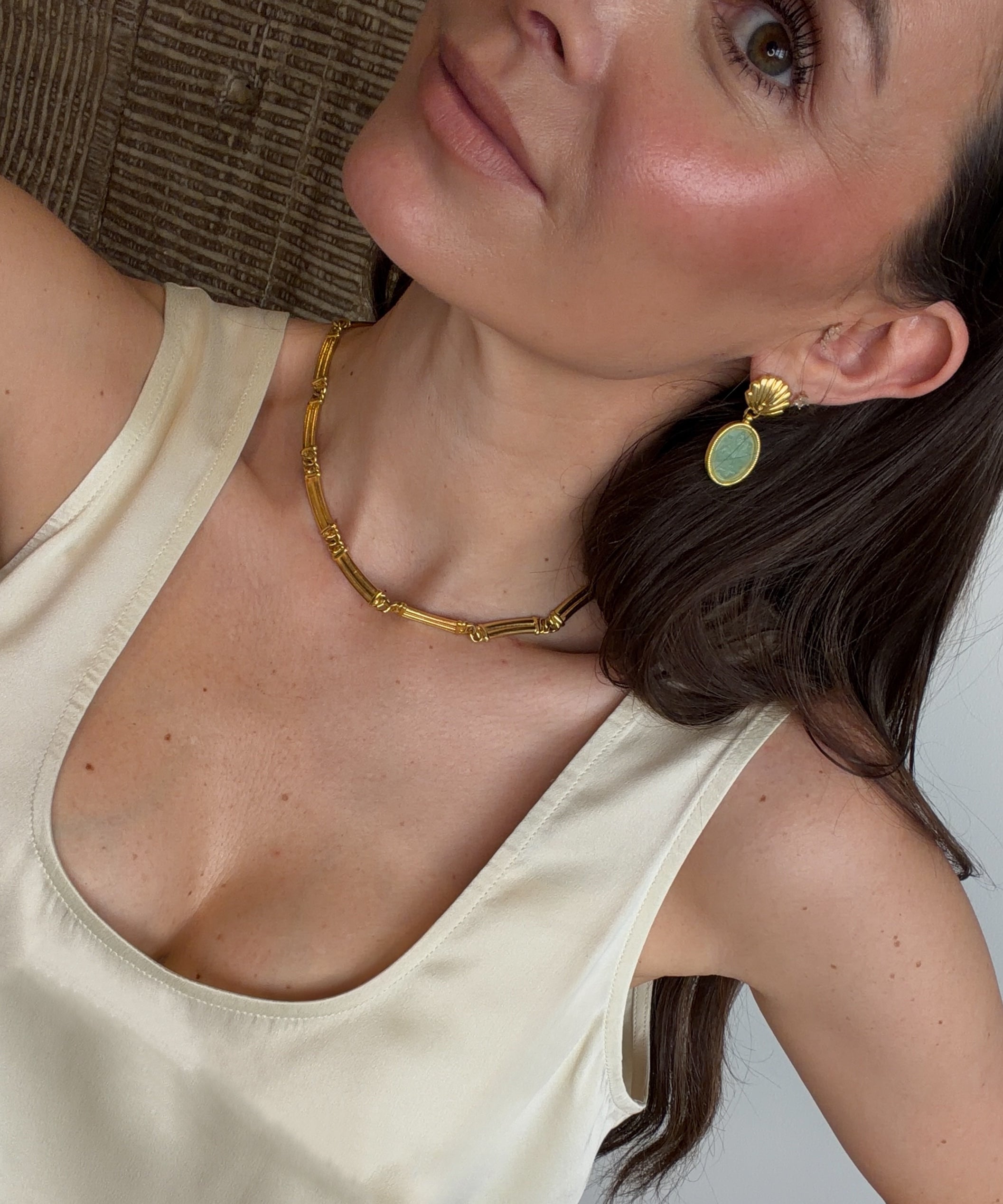 selfie shot of green earrings and silk cream vest 