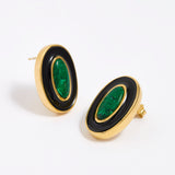 Close up image shot of gold earrings with green malachite stone and black enamel  on a white background