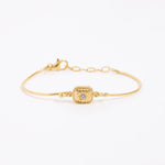 Gold bracelet with a decorative floral centre with a small crystal. set on a white background