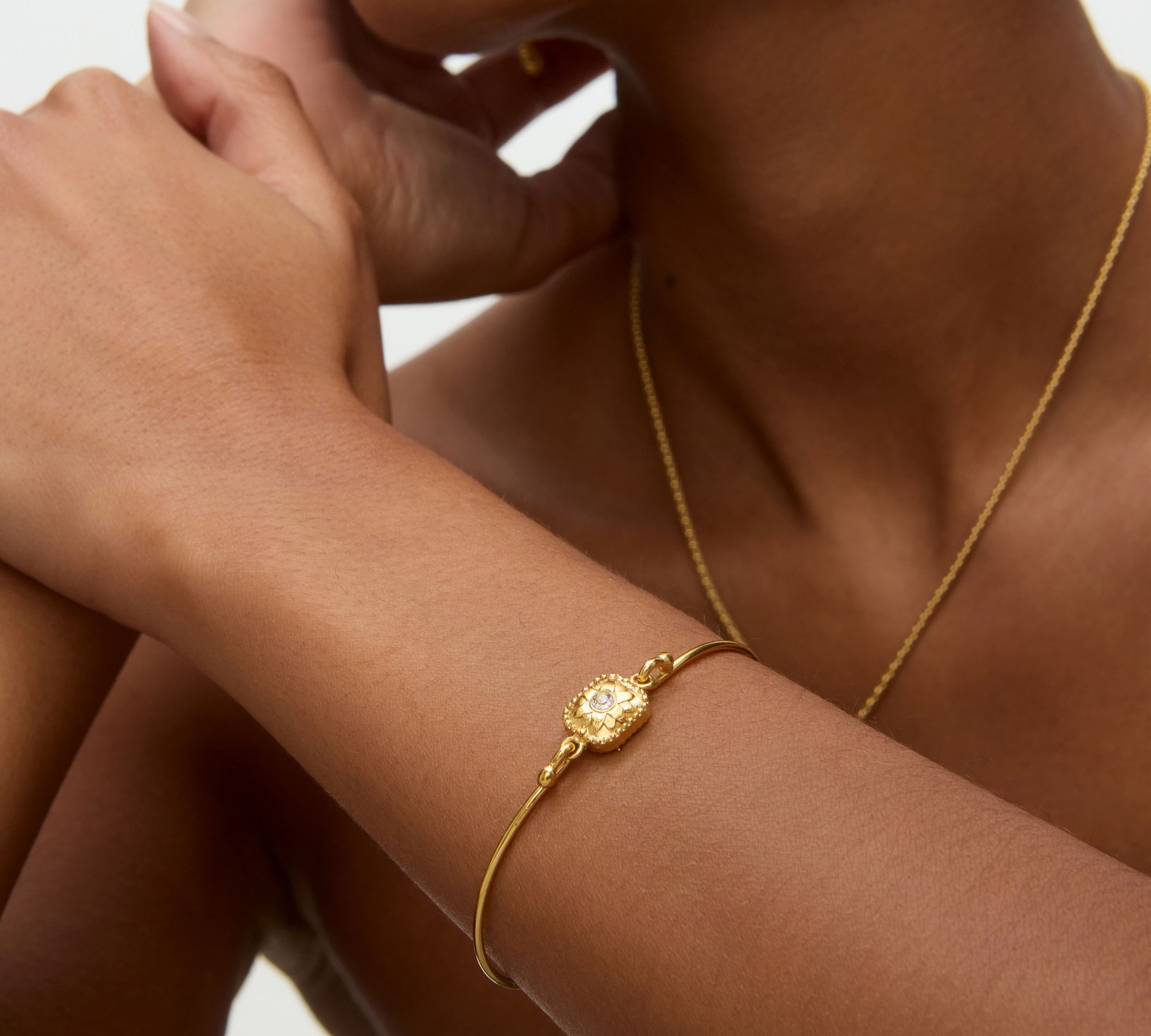 Gold bracelet on a wrist with a neutral background