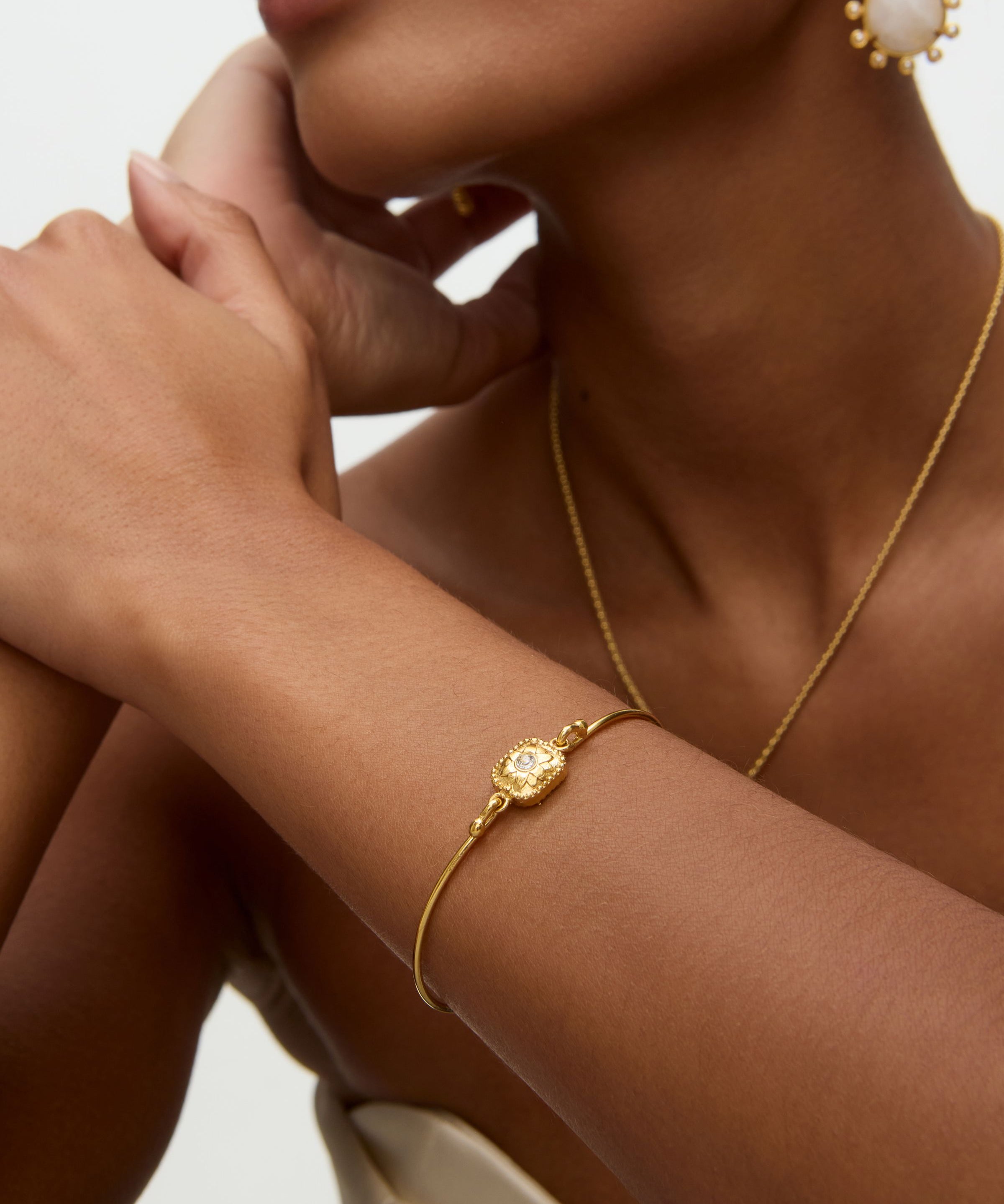 Gold bracelet on a wrist with a neutral background