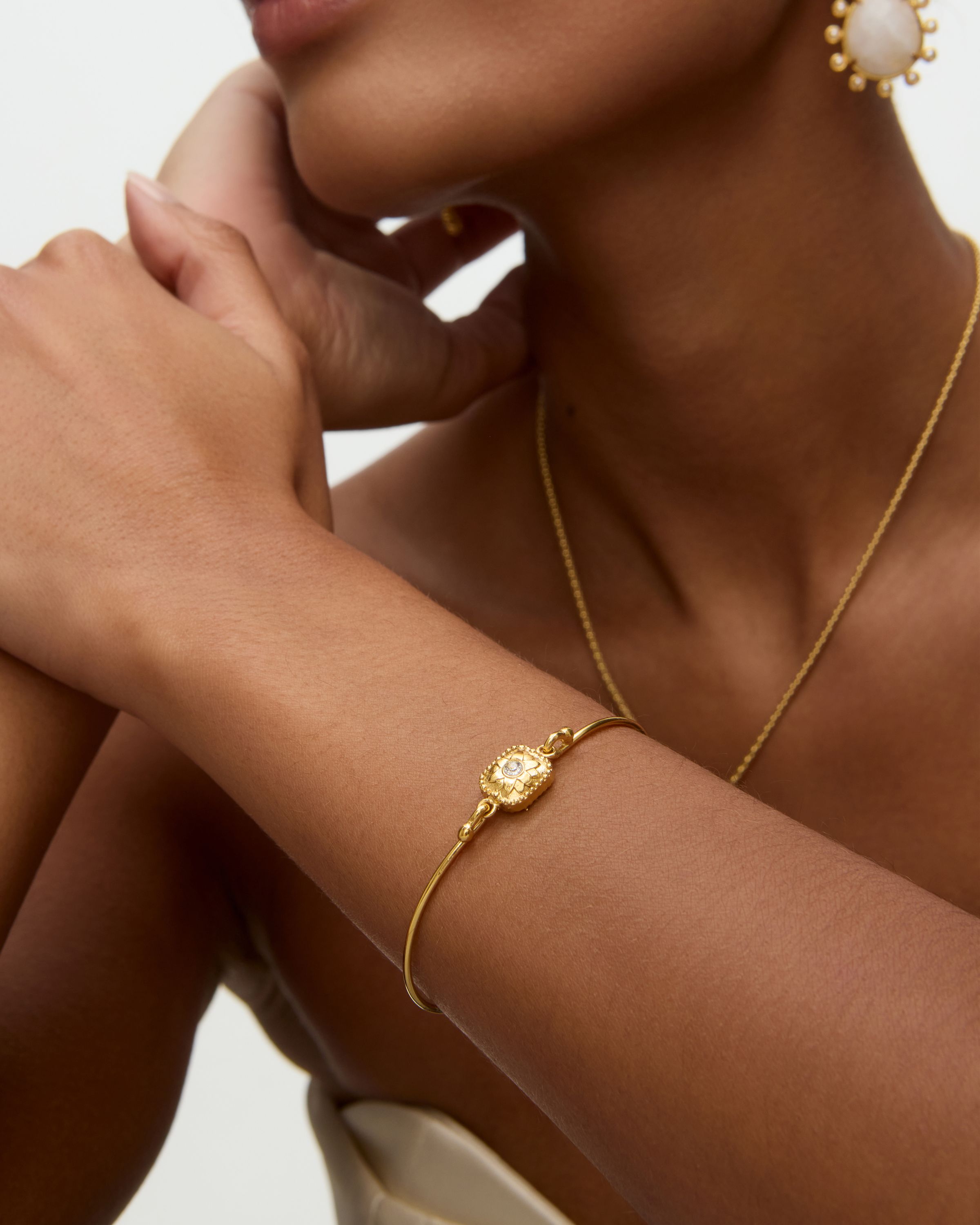 Gold bracelet on a wrist with a neutral background