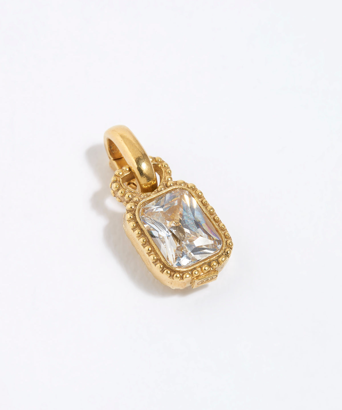 Gold charm pendant with a clear gemstone on a white background