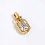 Gold charm pendant with a clear gemstone on a white background