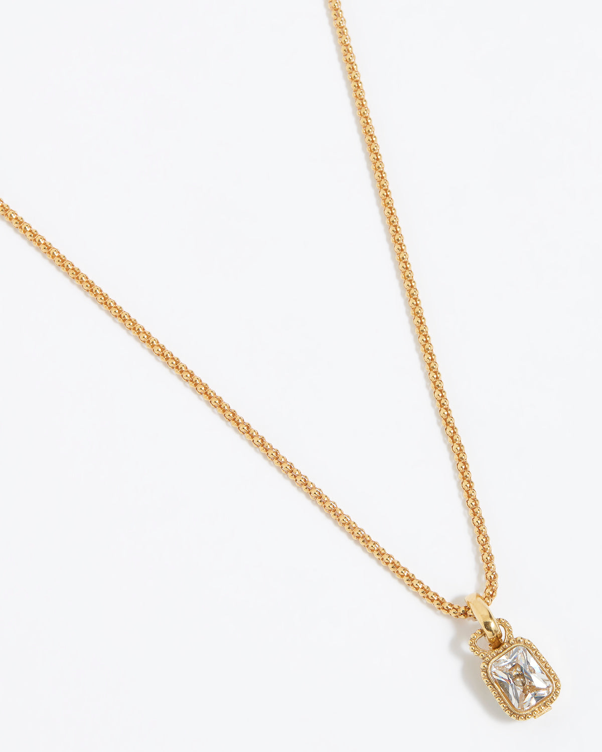 Gold charm pendant with a clear gemstone attached to gold rope chain, on a white background 