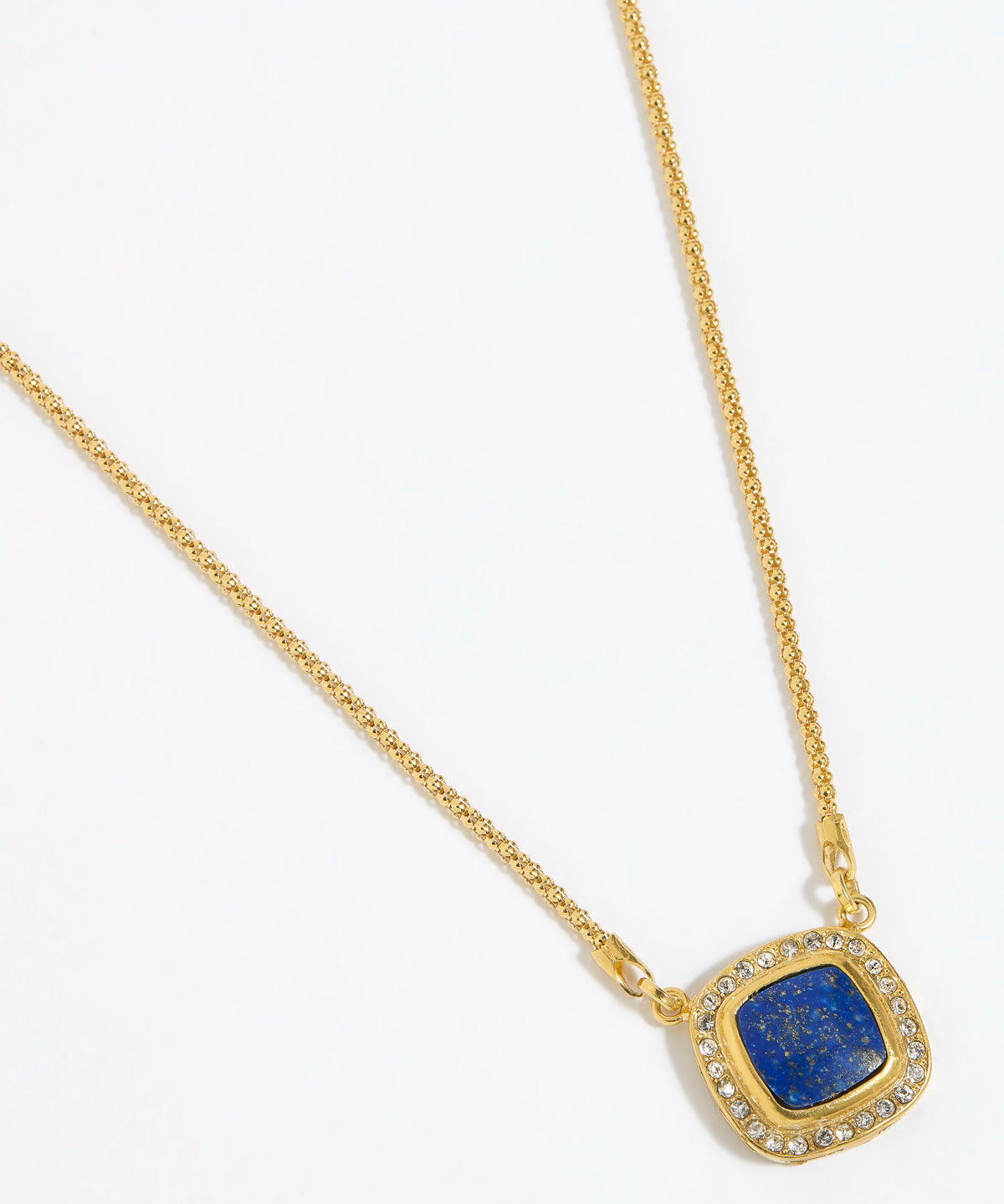 Gold necklace with a square blue pendant surrounded by crystals , on a white background