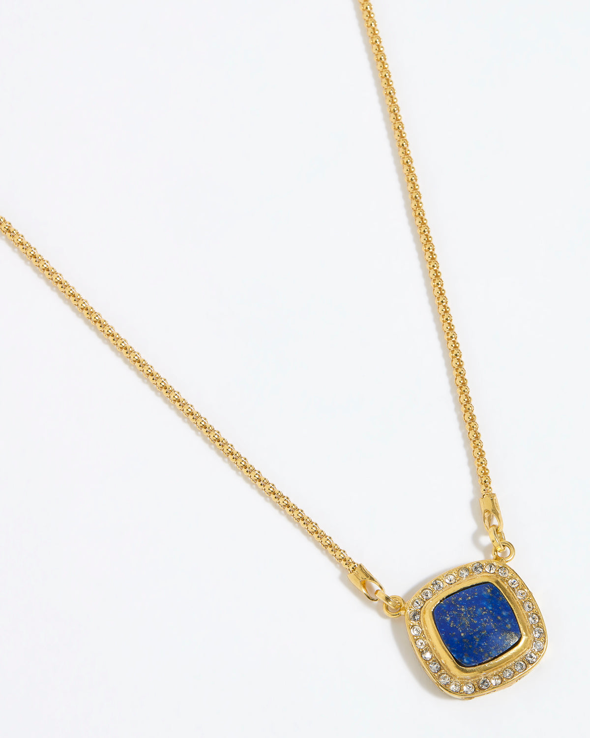 Gold necklace with a square blue pendant surrounded by crystals , on a white background