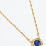 Gold necklace with a square blue pendant surrounded by crystals , on a white background