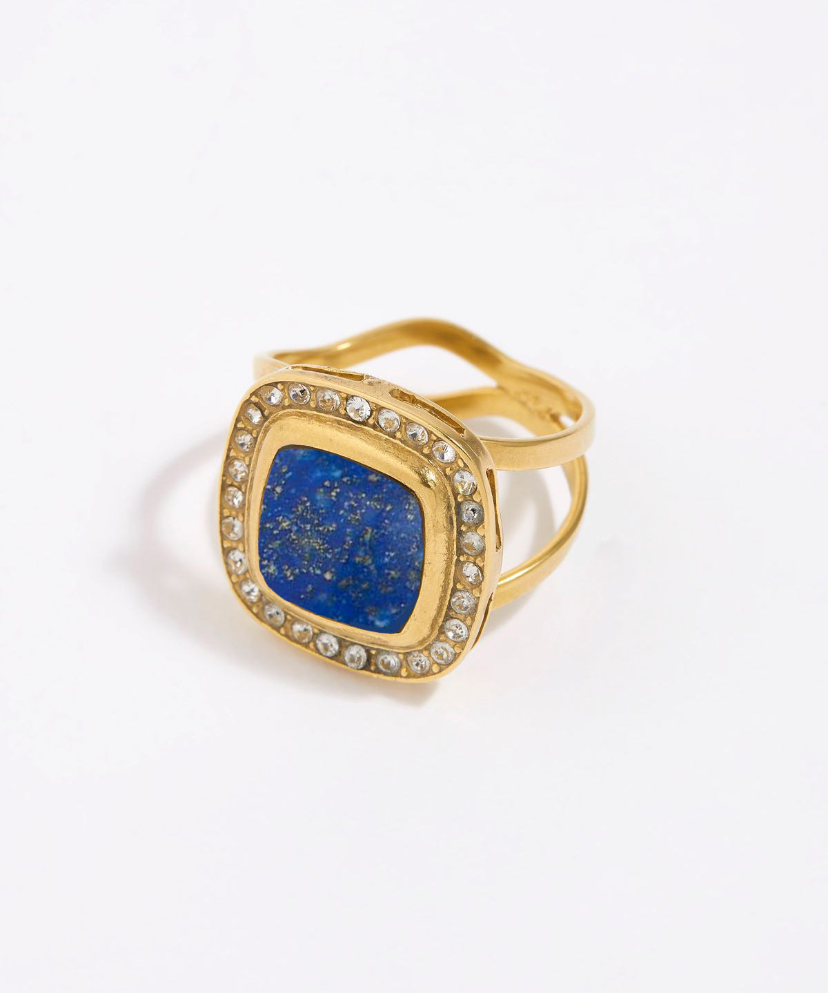 Gold ring with a blue lapis stone and clear gemstones on a white background