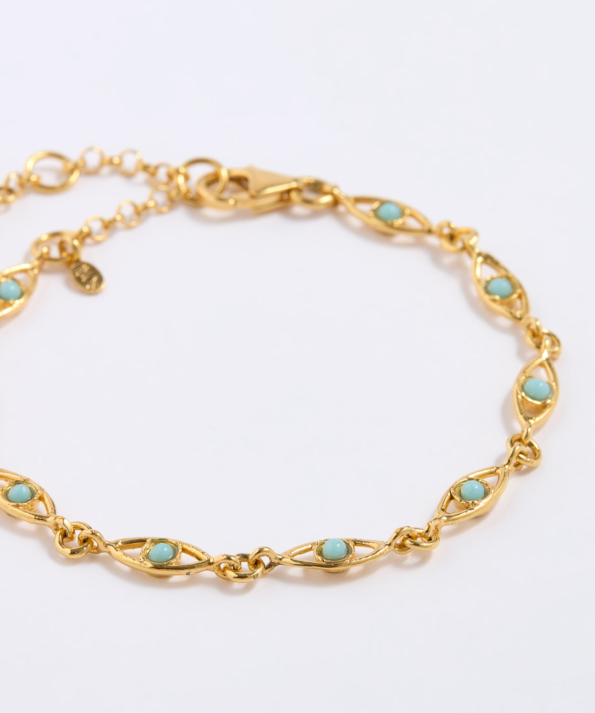 Gold bracelet with turquoise stones on a light gray background