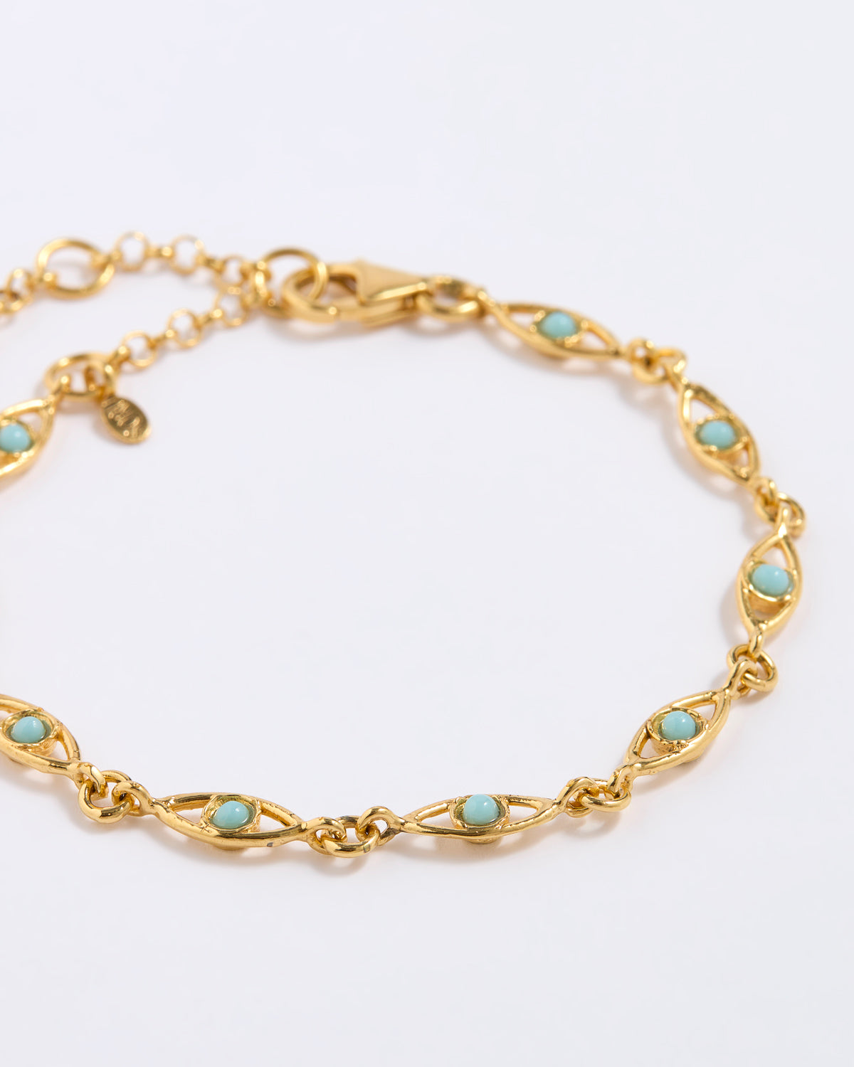 Gold bracelet with turquoise stones on a light gray background