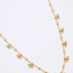 Gold coloured necklace with eye-shaped charms on a light gray background