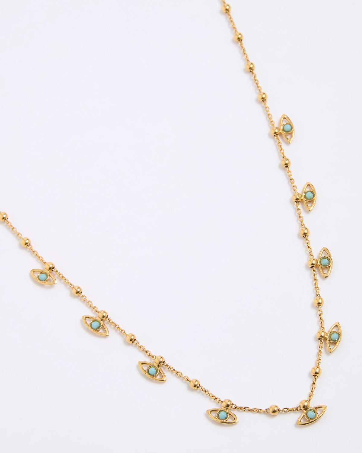 Gold coloured necklace with eye-shaped charms on a light gray background