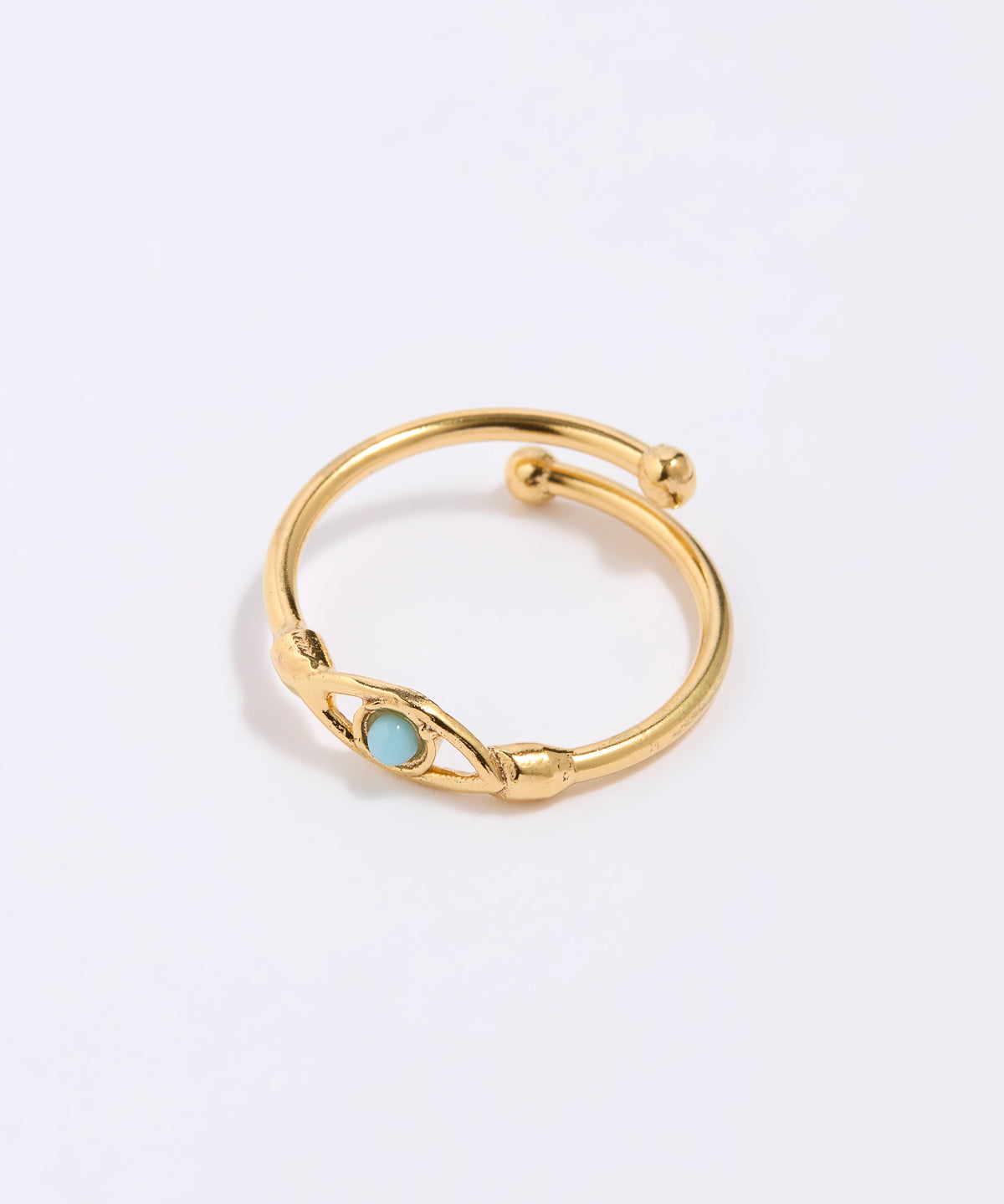 Gold coloured ring with a turquoise gemstone in the centre of evil eye. on a light gray background