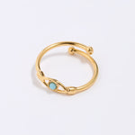 Gold coloured ring with a turquoise gemstone in the centre of evil eye. on a light gray background