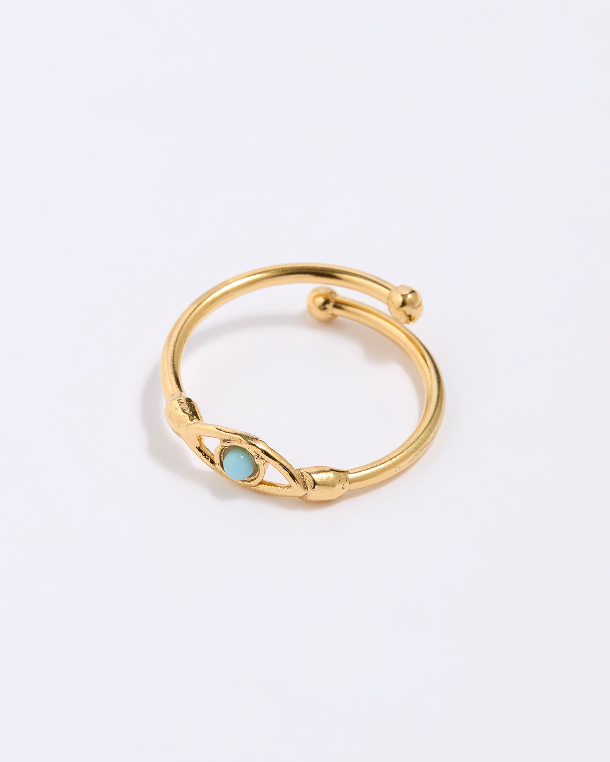Gold coloured ring with a turquoise gemstone in the centre of evil eye. on a light gray background
