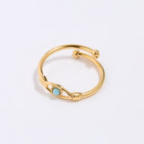 Gold coloured ring with a turquoise gemstone in the centre of evil eye. on a light gray background