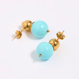 Pair of earrings with gold and turquoise beads on a white background