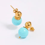 Pair of earrings with gold tops and turquoise beads on a white background