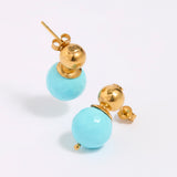 Pair of earrings with gold tops and turquoise beads on a white background