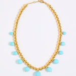 Gold coloured beaded necklace with turquoise beads on a white background