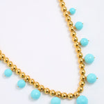 Necklace with gold beads and turquoise stones on a white background