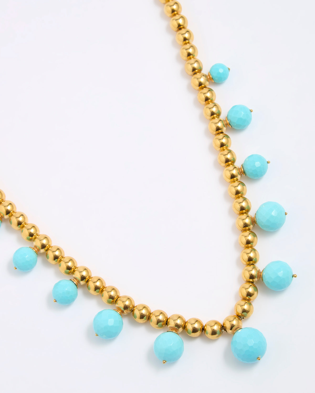 Necklace with gold beads and turquoise stones on a white background