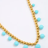 Necklace with gold beads and turquoise stones on a white background