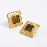 Gold square earrings with a central tigers eye gemstone on a white background