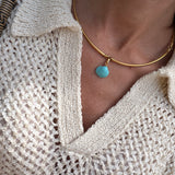 Close-up of model wearing a gold coloured choker with a turquoise shell pendant.