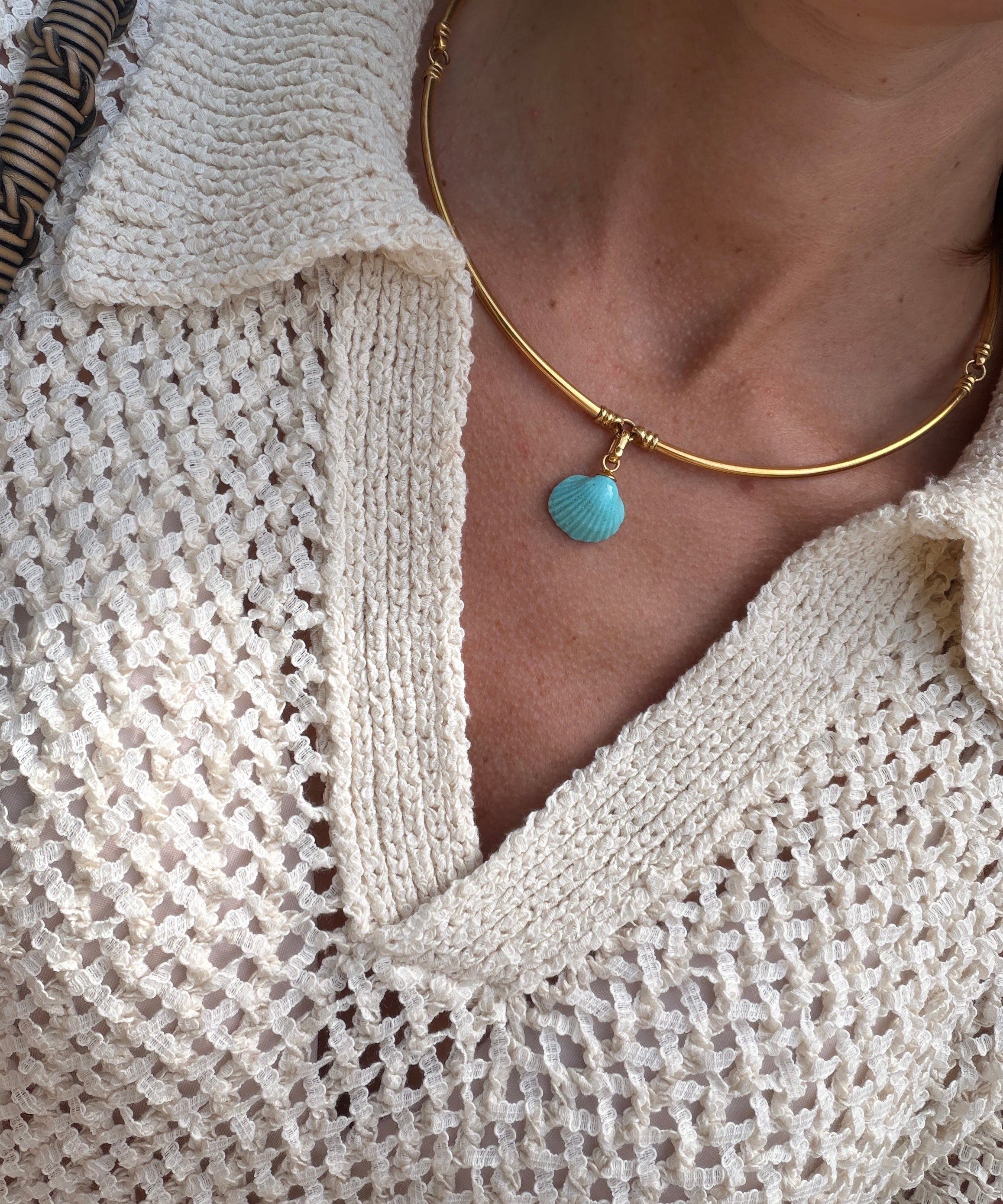 Close-up of model wearing a gold coloured choker with a turquoise shell pendant.