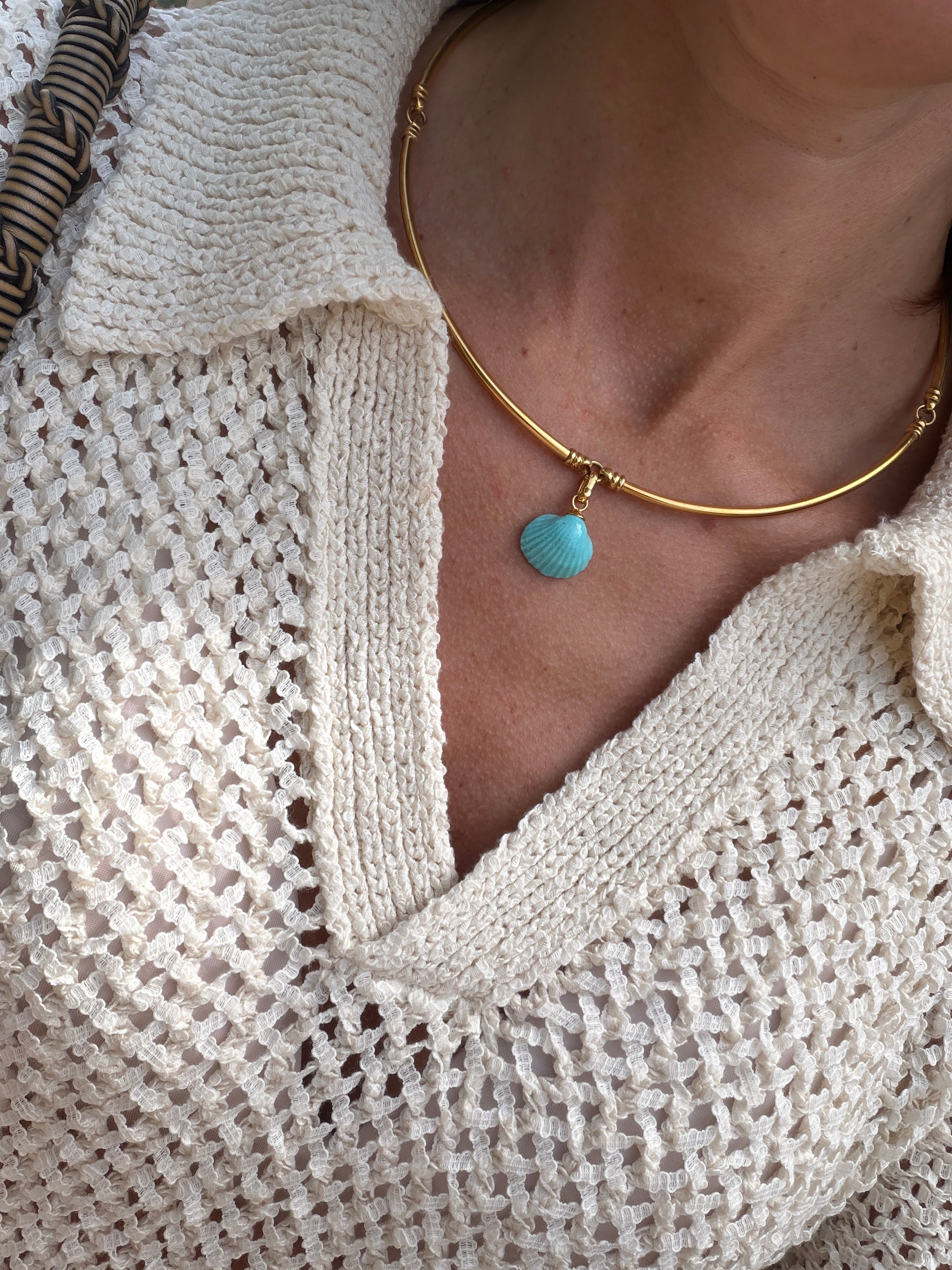 Close-up of model wearing a gold coloured choker with a turquoise shell pendant.