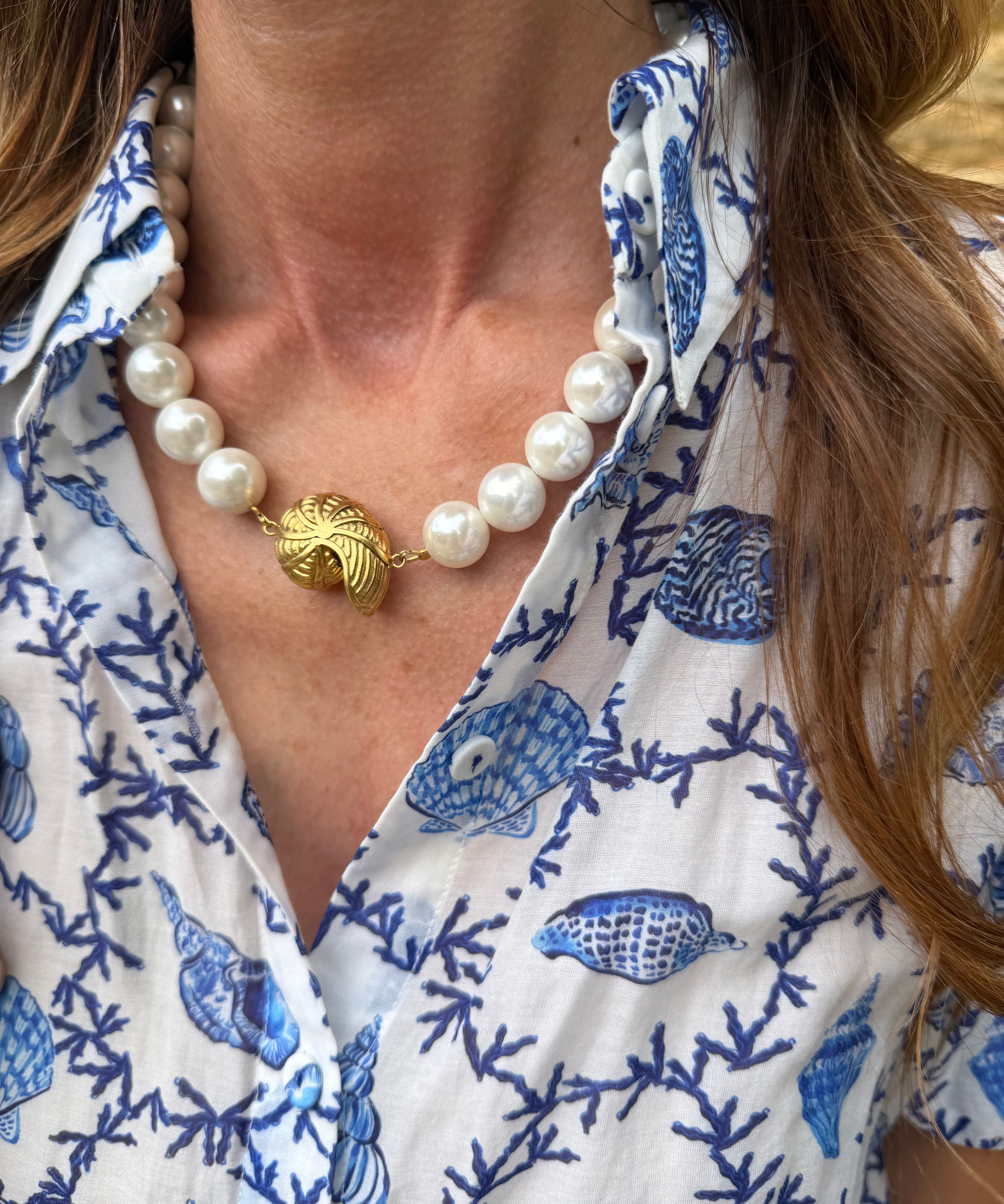 Close-up of a person wearing a blue and white patterned shirt with a pearl necklace.