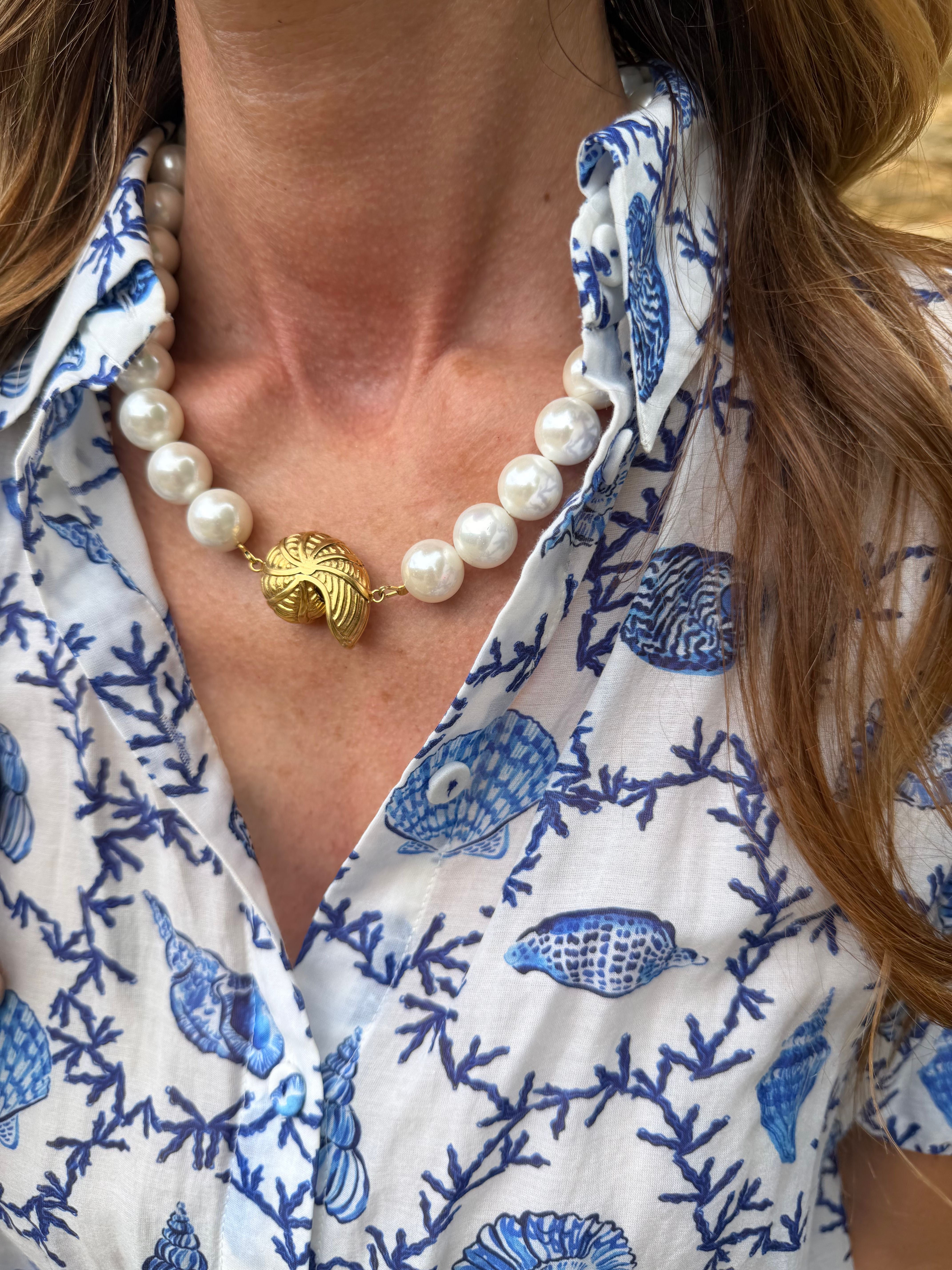 Close-up of a person wearing a blue and white patterned shirt with a pearl necklace.