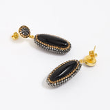 Pair of earrings with black stones and gold accents on a white background