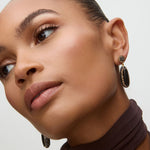 Close-up of a woman wearing black onyx earrings with a neutral background