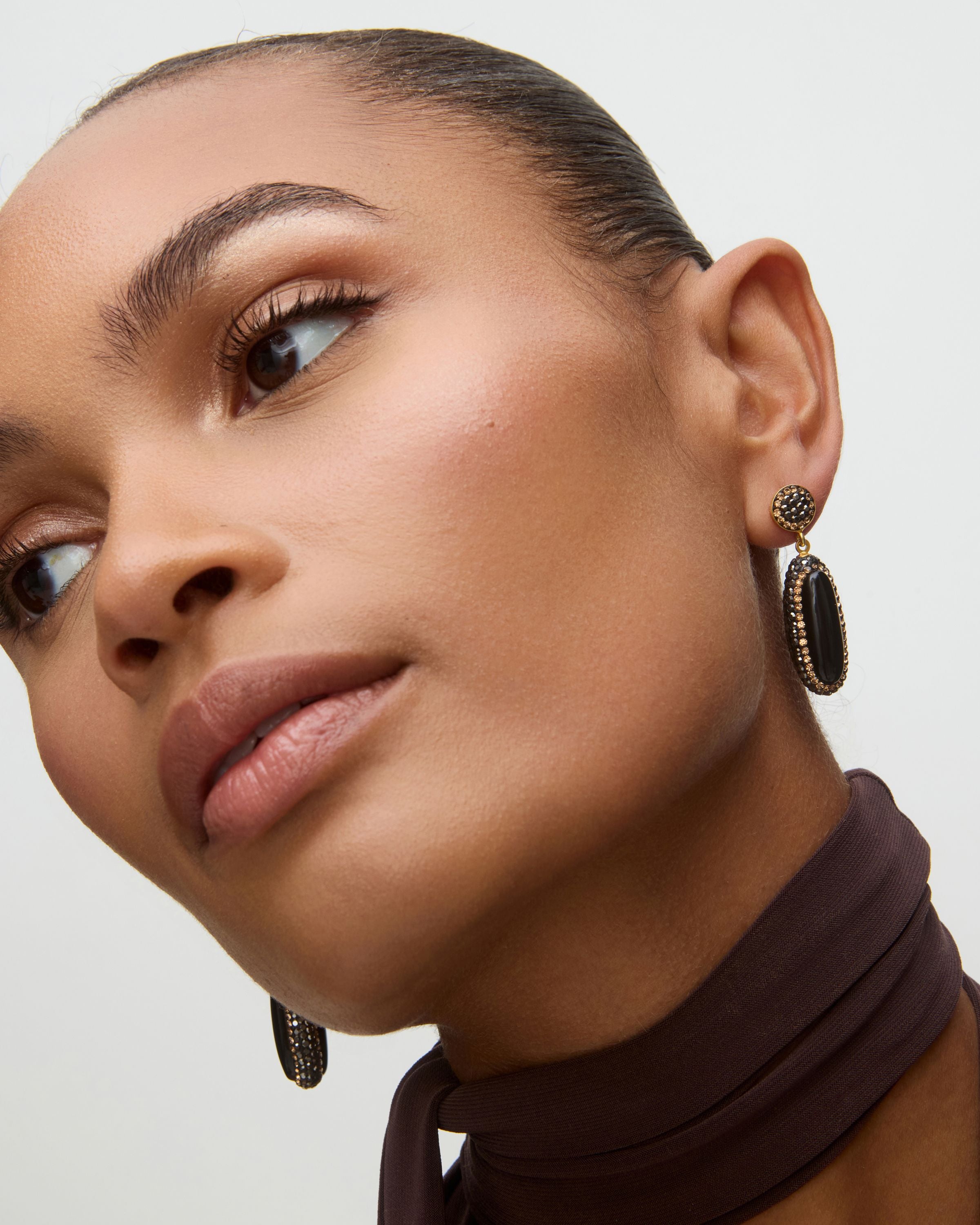 Close-up of a woman wearing black onyx earrings with a neutral background