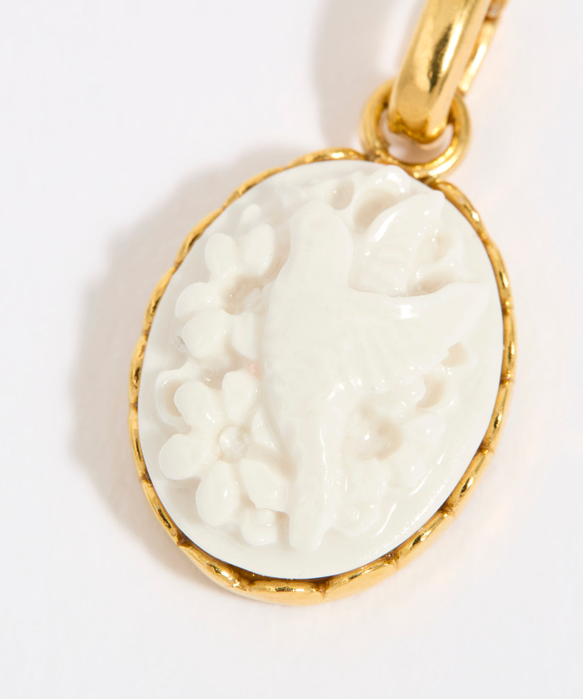 Gold coloured pendant with a white cameo on a light background