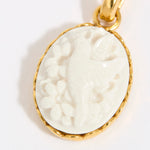 Gold coloured pendant with a white cameo on a light background
