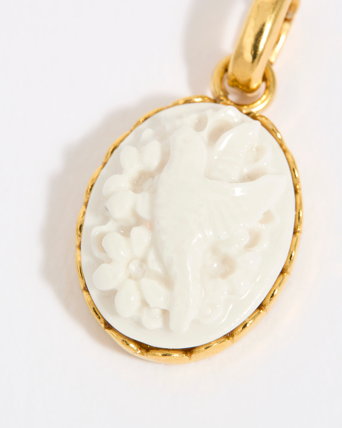Gold coloured pendant with a white cameo on a light background