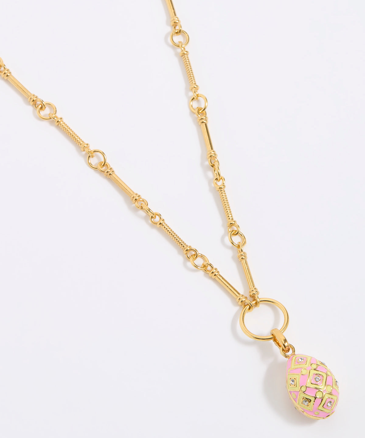 Gold necklace with a pink and gold egg shaped pendant on a light gray background