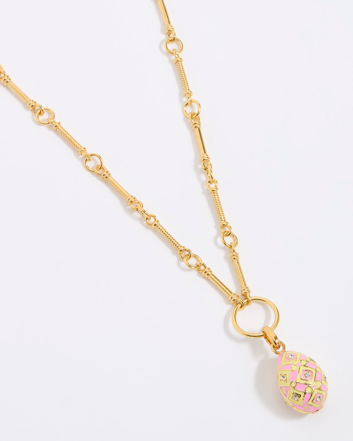Gold necklace with a pink and gold egg shaped pendant on a light gray background