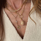 showing the pink egg charm attached to a chain and worn as part of a layering of gold necklaces 
