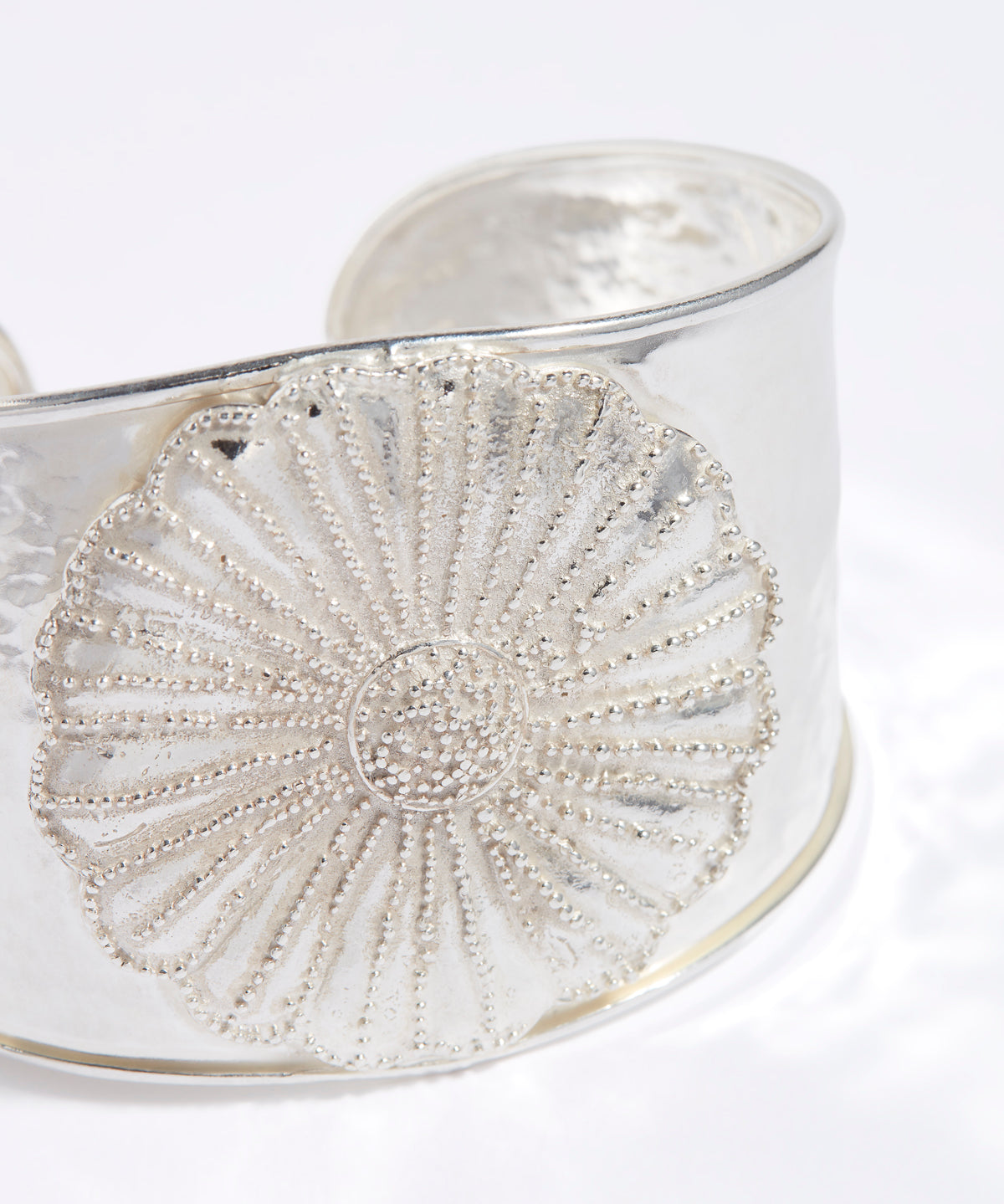 Silver bracelet with intricate floral design on a white background
