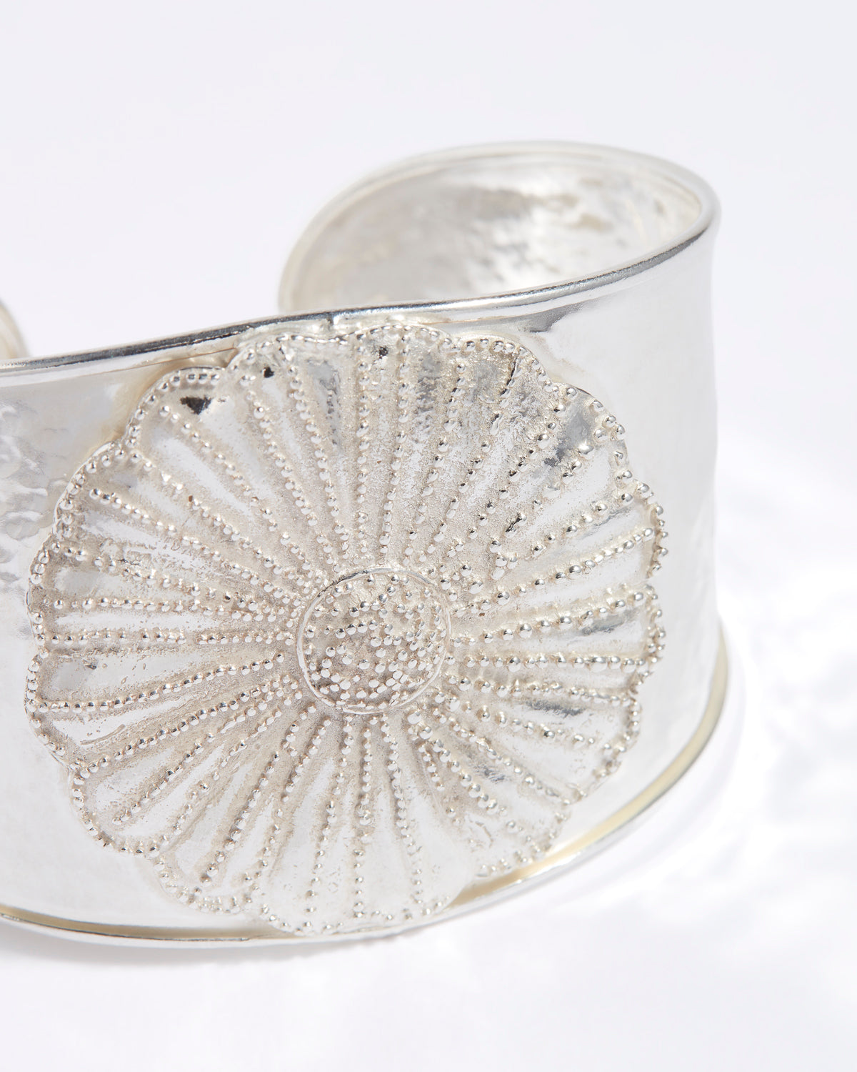 Silver bracelet with intricate floral design on a white background